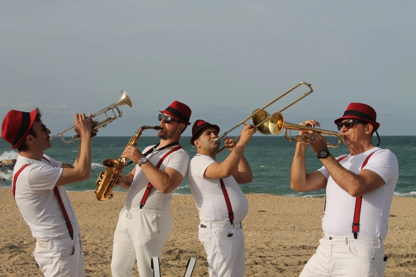 Sahilde trompet, saksafon ve trombon çalan bando ekibi